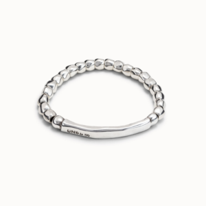 Allow yourself to be swept away by this beautiful piece and wear it in style on any occasion. This original rigid silver-plated bracelet is comprised of a cluster of irregular stones, lending it a natural and truly unique look. At its center is a smooth elongated piece with our logo engraved on it.