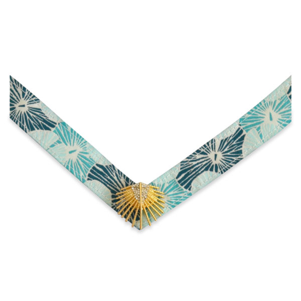 The Georgia strap is a turquoise, teal, and white fabric floral strap with a gold palm leaf ornament.